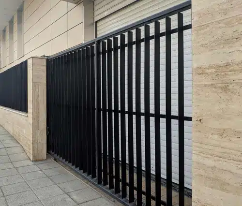 Flat-top black aluminum fence and sliding gate along a commercial walkway