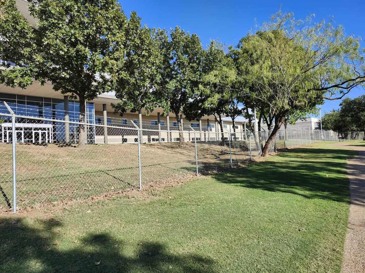 Galvanized chain-link fence line securing a grassy commercial property