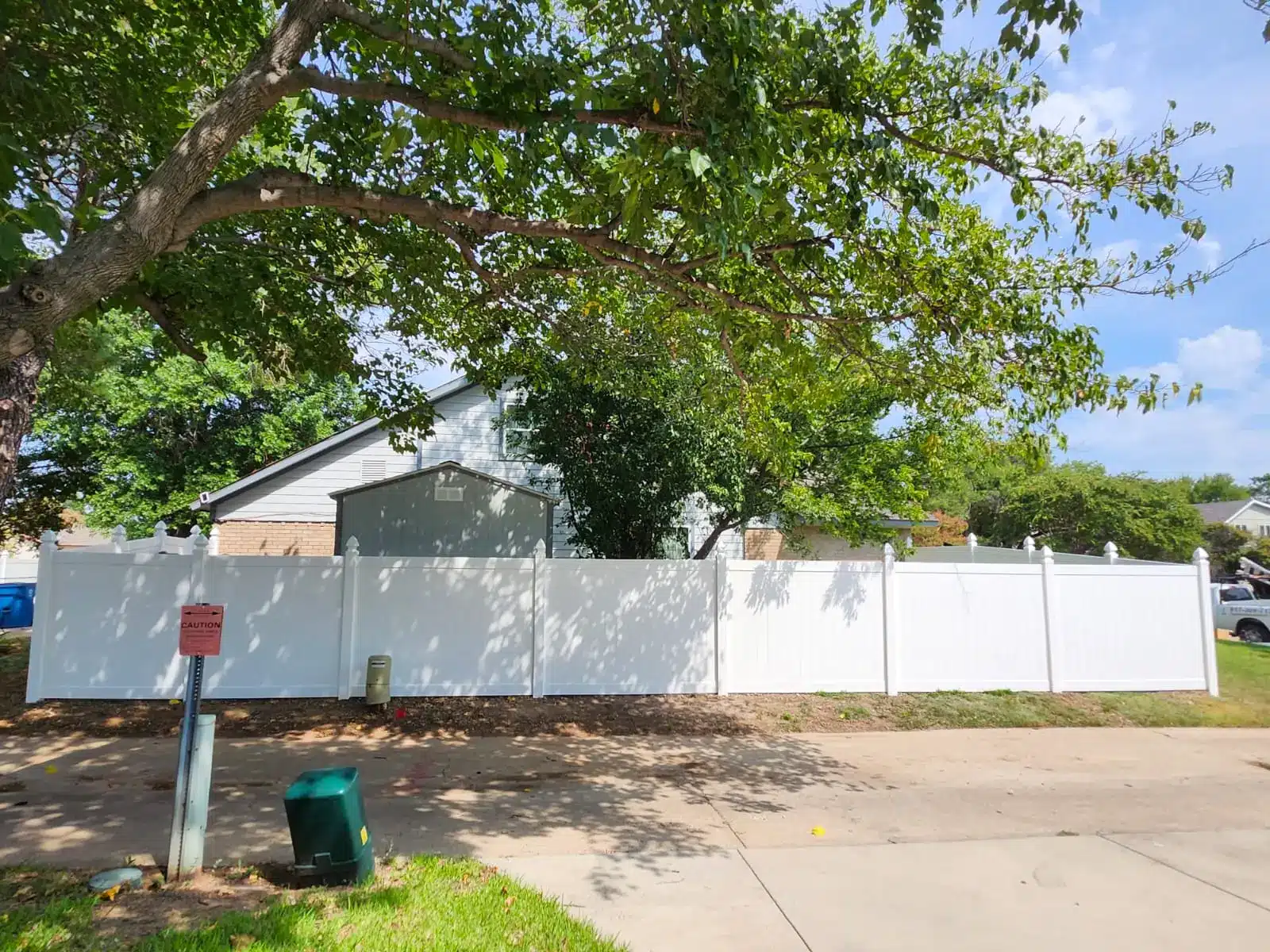 White vinyl privacy fence with decorative post caps along a residential street
