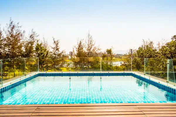 Frameless glass pool fence panels surrounding a blue-tiled swimming pool