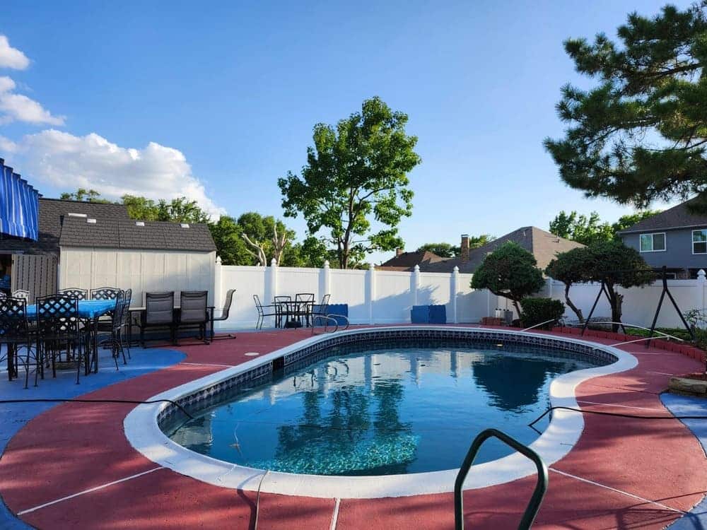 White privacy fence enclosing a backyard swimming pool