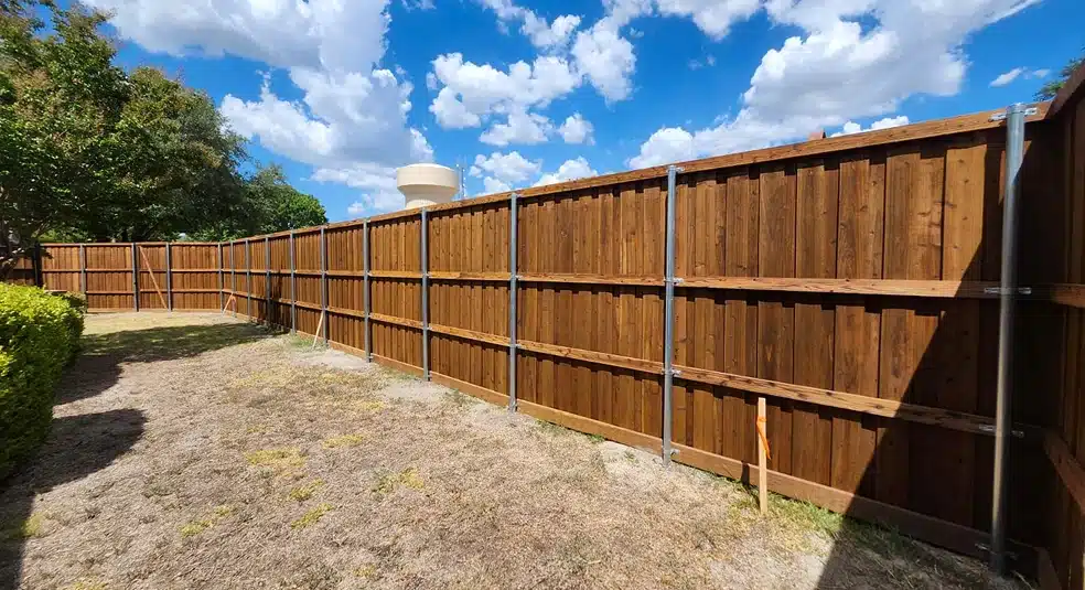 Tall stained cedar board-on-board privacy fence with steel posts