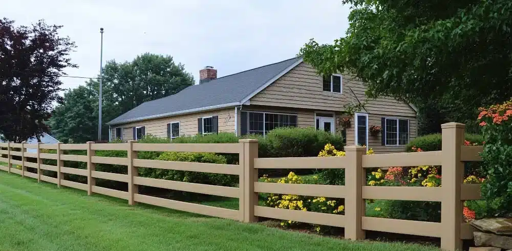 Tan four-rail fence running along a landscaped front yard