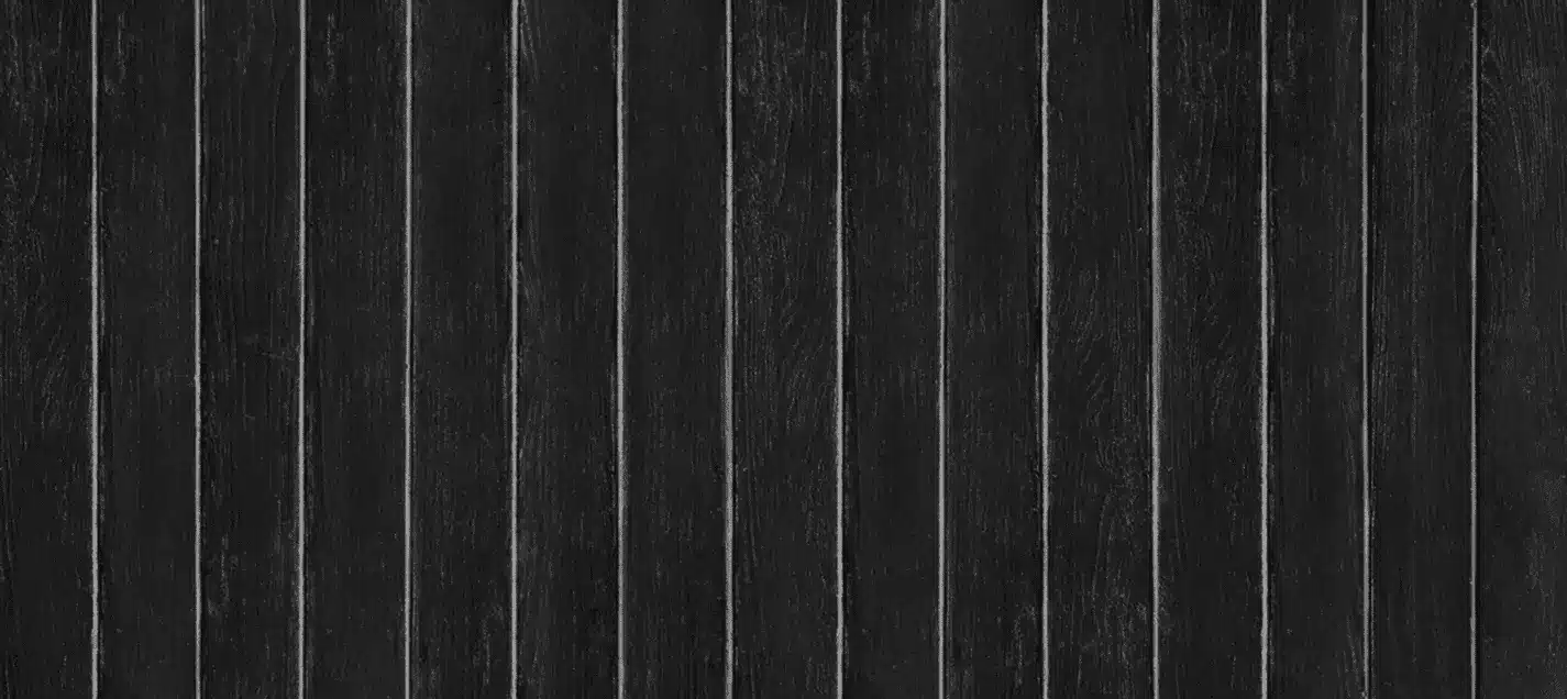 Close-up of black wood-grain vinyl fence boards, one of the wood-look finish options