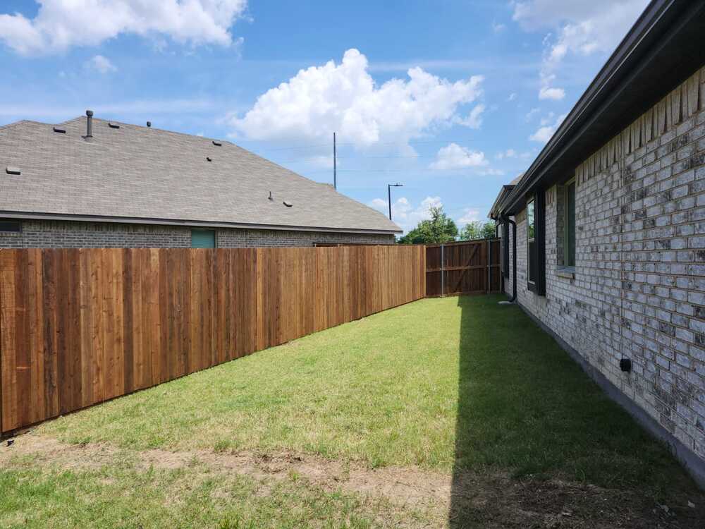 New cedar fence enclosing a backyard between two brick homes